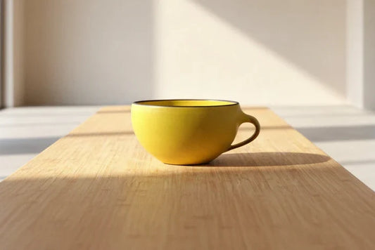 Yellow mug on a wooden table with sunlight casting shadows