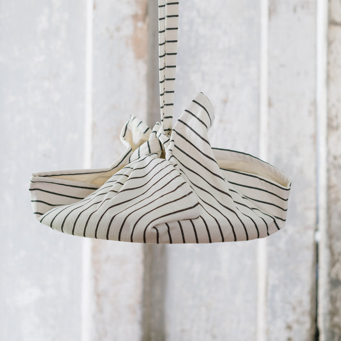 A folded striped picnic bag with a sling, hanging against a white background.