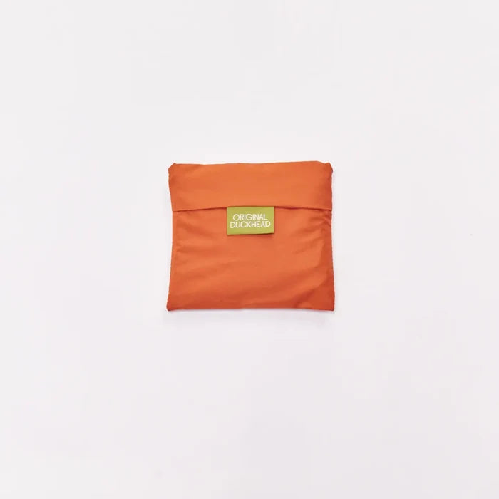 An orange compact pouch with a small green label reading 'ORIGINAL DUCKHEAD' in the center, set against a plain white background.