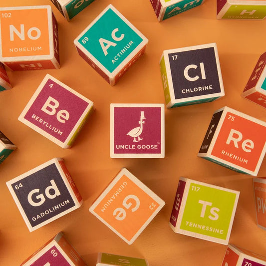 A collection of colorful wooden blocks with elements from the periodic table, including Hydrogen, Oxygen, Nitrogen, etc., each with their atomic number and symbol.